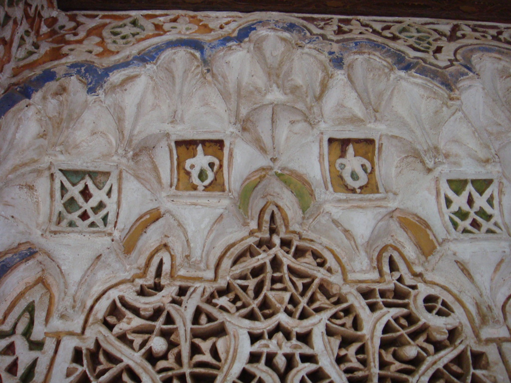 Detail van Marokkaans stucwerk met geometrische patronen en gekleurde mozaïektegels.