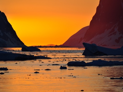 Zonsondergang boven ijsbergen en besneeuwde bergen in Antarctica tijdens de Route Antarctica.
