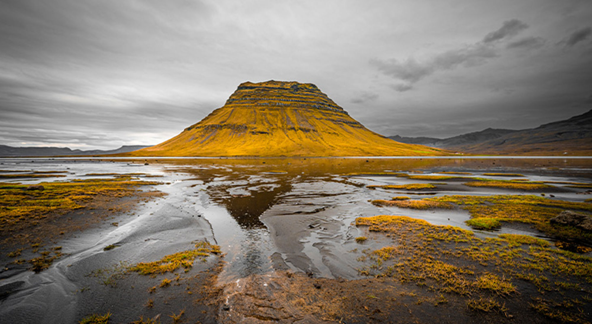 Eyjafjallajökull vulkaan IJsland Berg met spiegeling in ondiep water en moslandschap onder een bewolkte lucht.