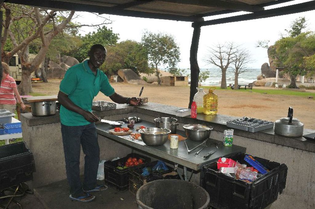 Kok bereidt maaltijd in openluchtkeuken bij Lake Malawi tijdens groepsrondreis Zambia, Malawi en Tanzania.