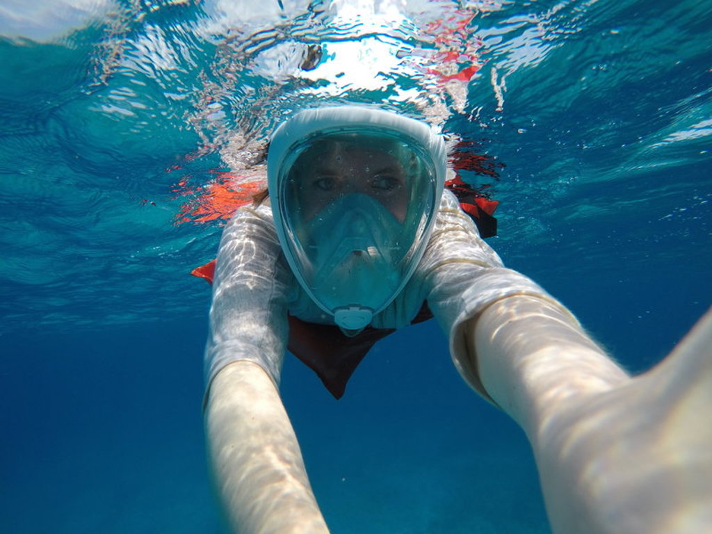 Snorkelaar met volgelaatsmasker onder water tijdens familiereis Mexico.