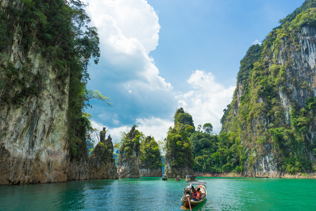 Longtailboot op helderblauw meer tussen hoge kalksteenkliffen in Thailand tijdens 22-35ers reis Thailand.