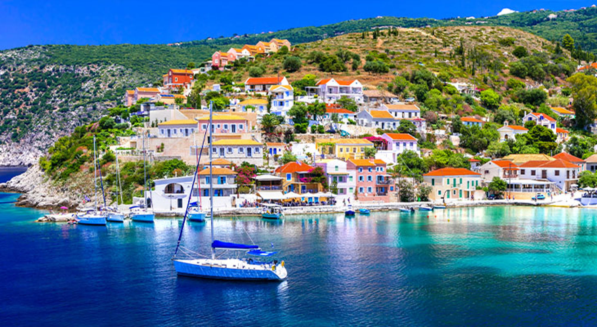 Kefalonia Kleurrijk kustdorp met zeilboot in een turquoise baai.