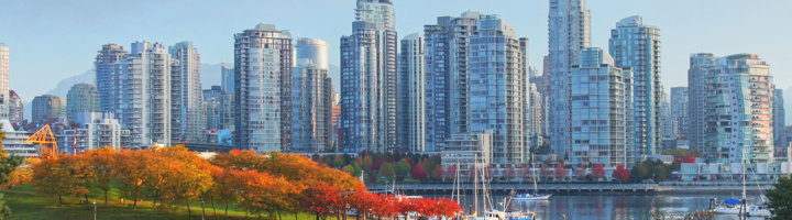 Skyline van Vancouver met moderne wolkenkrabbers, herfstkleuren in het park en boten in de haven.