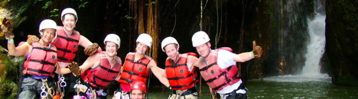 Canyoninggroep met helmen en reddingsvesten bij waterval in het regenwoud van Costa Rica.
