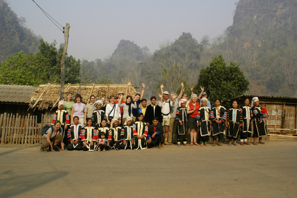 Groepsrondreis Thailand: reizigers poseren met lokale bewoners in traditionele kleding in een bergdorp.