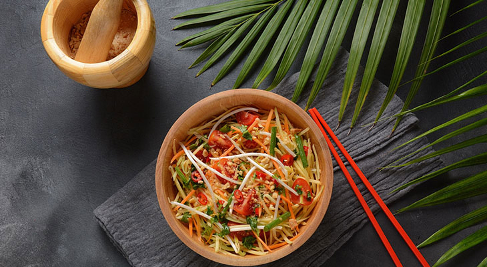 Vegetarisch Thais gerecht Kom Aziatische noedelsalade met groenten, chili en taugé in houten kom met rode eetstokjes.