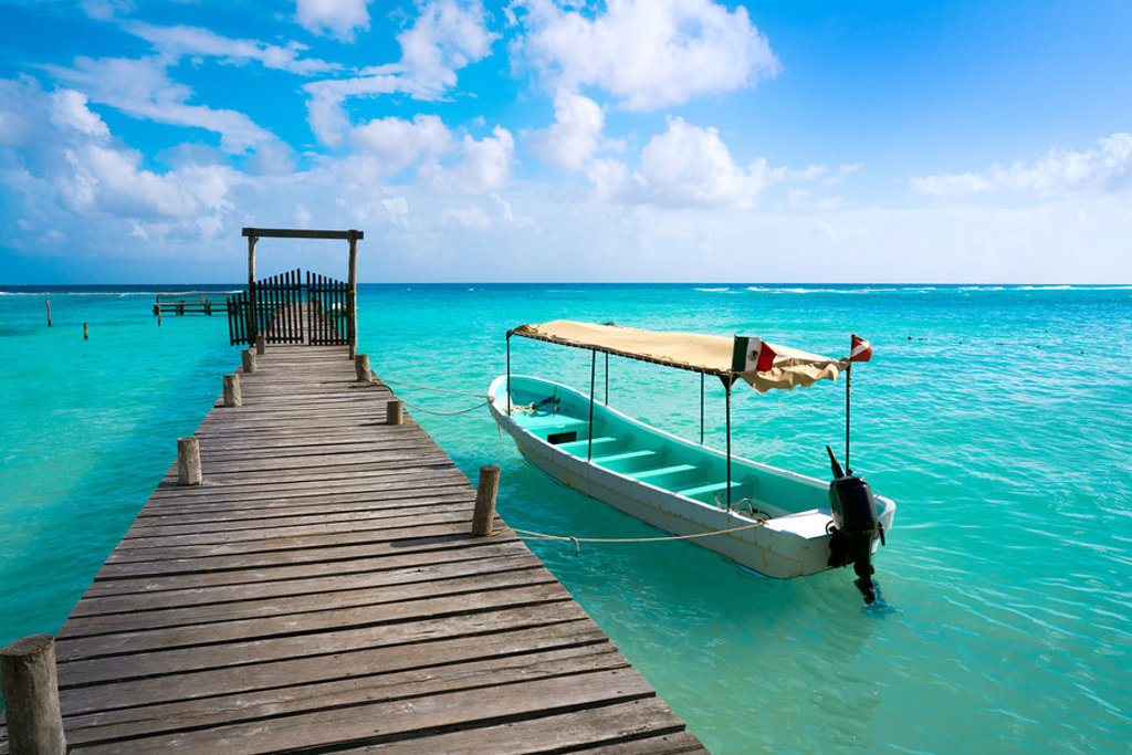 Houten steiger met boot op turquoise zee tijdens groepsrondreis Mexico.