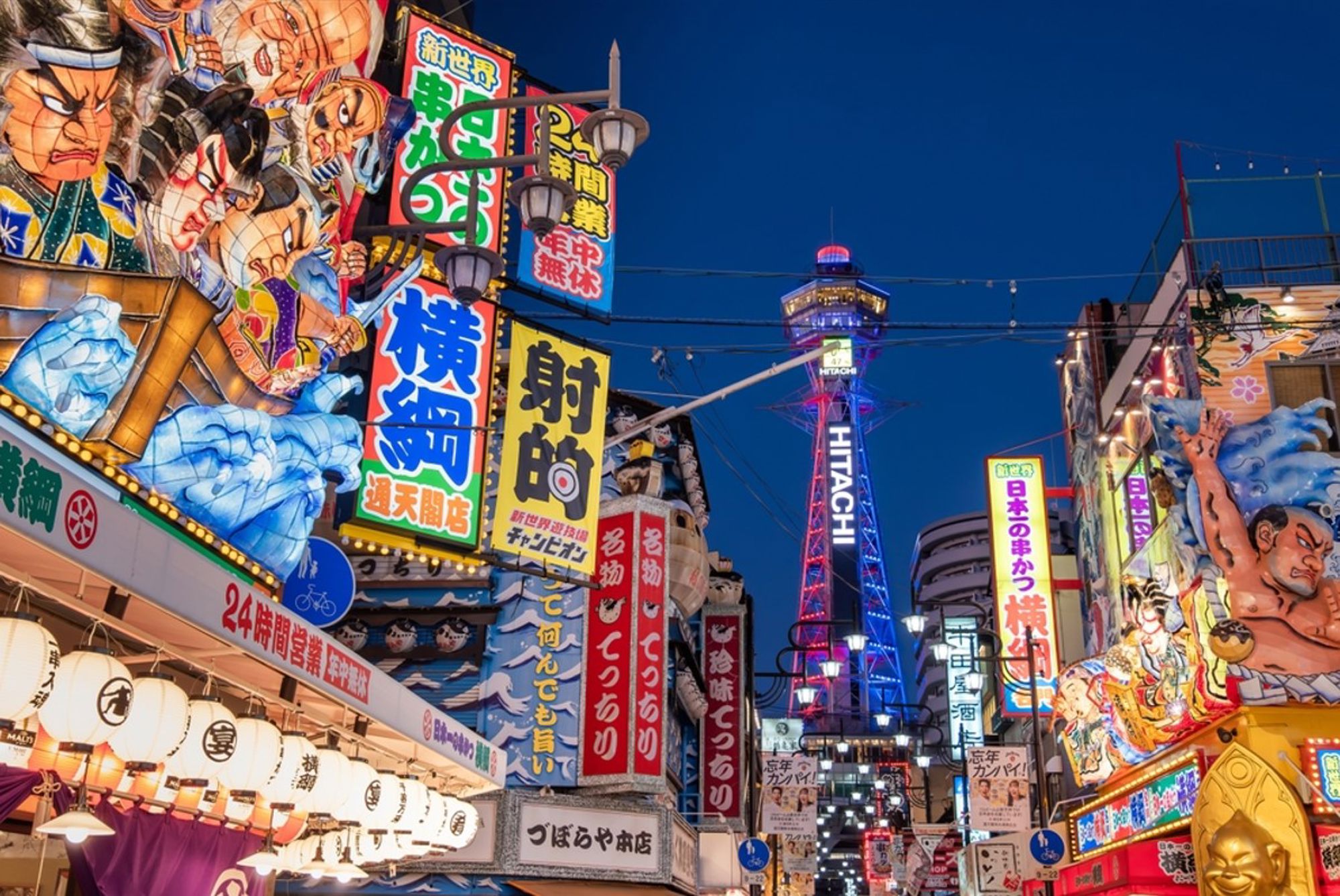 Verlichte neonreclames in Osaka met de Tsutenkaku-toren in de avond.