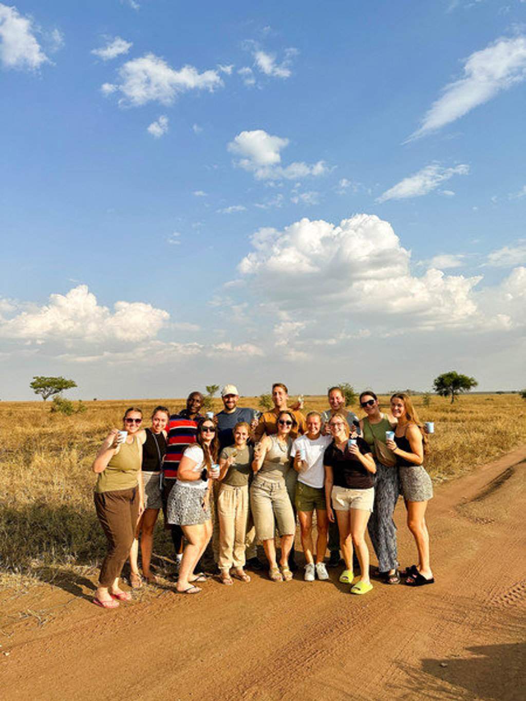 Groep 22-35ers tijdens rondreis Kenia & Tanzania op de savanne, bij een zandweg onder een blauwe lucht.