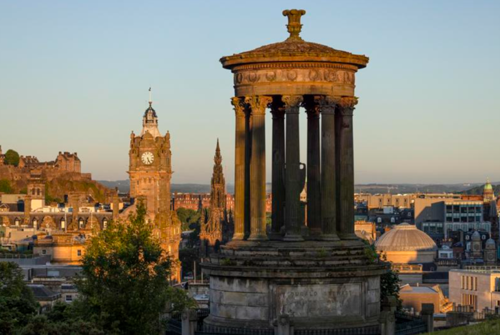 Uitzicht over Edinburgh met het Dugald Stewart Monument en de Balmoral-klokkentoren tijdens zonsondergang.