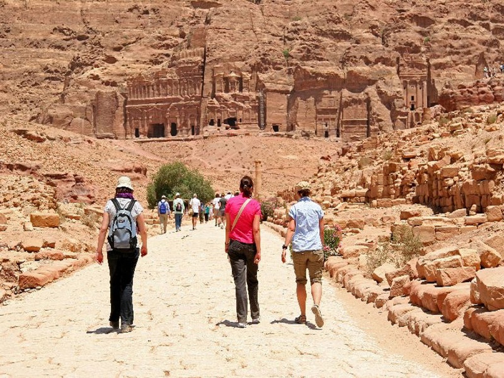 Wandelaars op de hoofdstraat van Petra, Jordanië, met rotsgraven op de achtergrond.