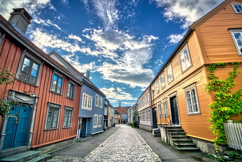 Kleurrijke houten huizen langs een rustige kasseienstraat in Noorwegen tijdens een groepsrondreis.