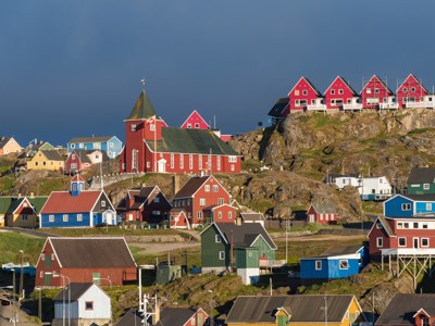 Kleurrijke huizen en rode kerk op rotsachtige heuvel in Nuuk, Groenland.