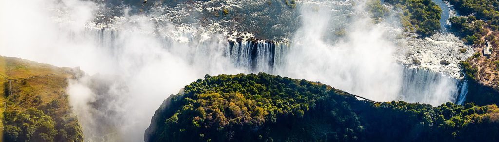Panorama van de Victoriawatervallen met nevel boven de Zambezi, hoogtepunt van een groepsrondreis Zuidelijk Afrika.