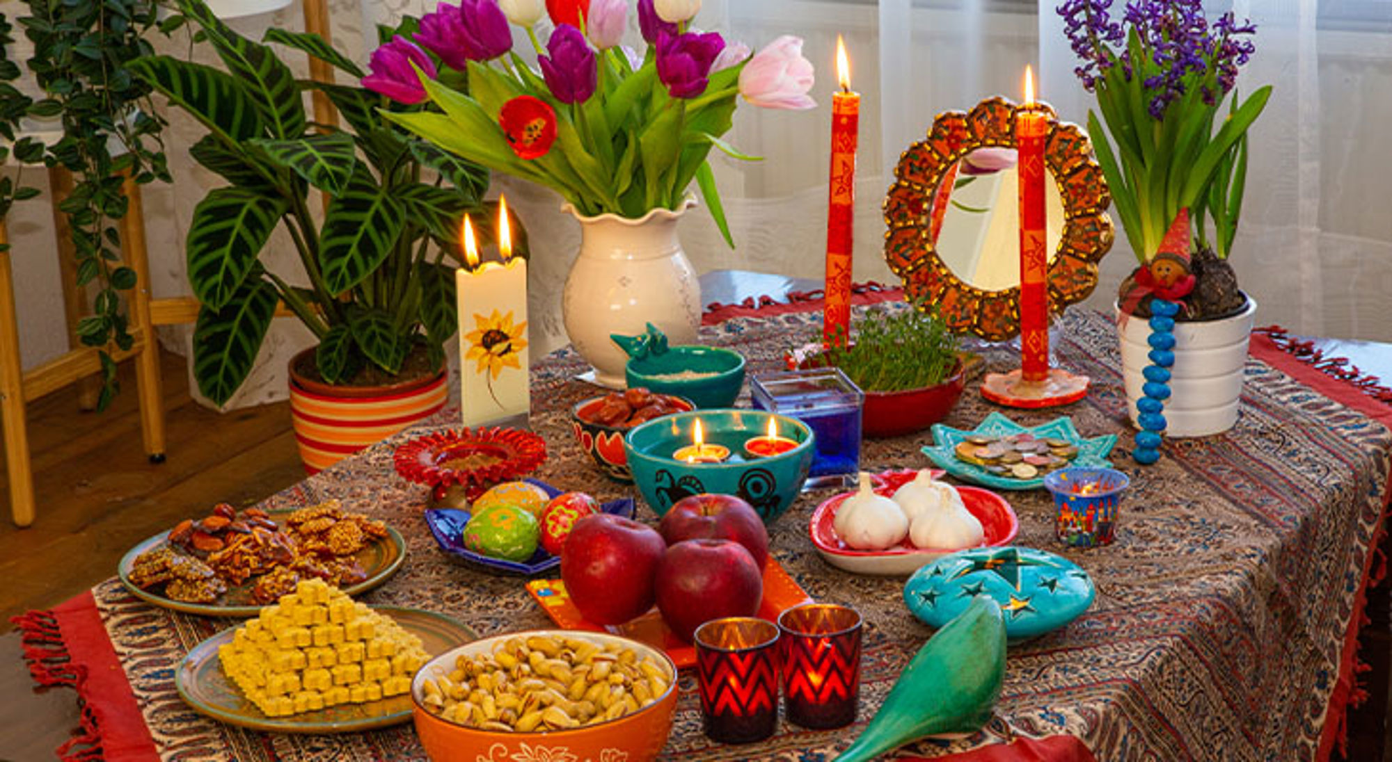 Nowruz Centraal-Azië Haft-sin tafel voor Nowruz met kaarsen, tulpen, fruit, noten en beschilderde eieren.