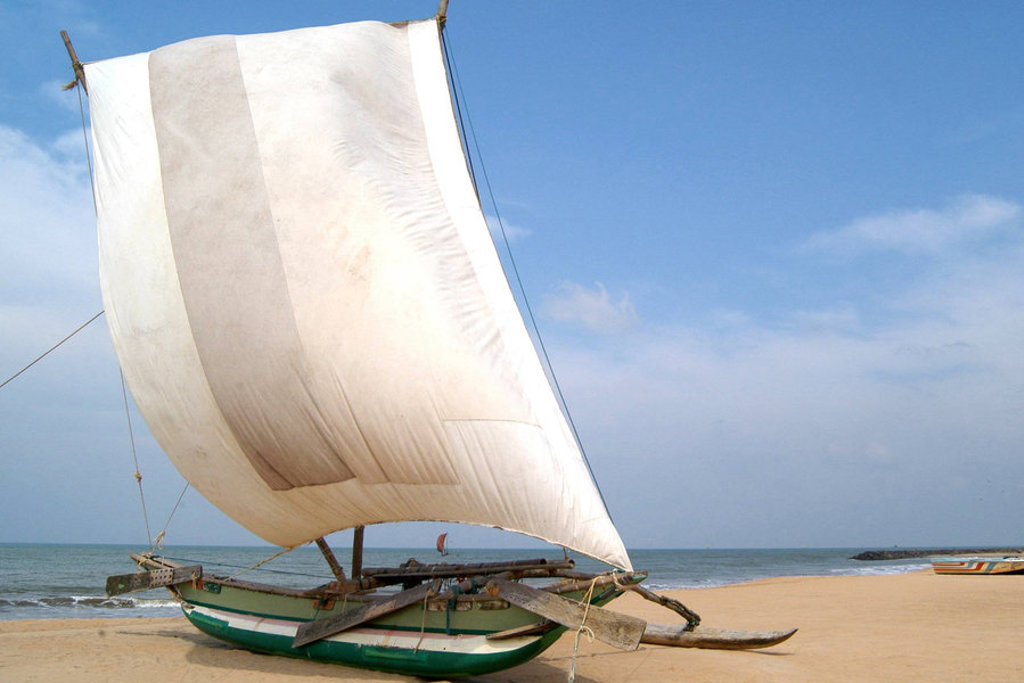 Traditionele vissersboot met wit zeil op het strand in Sri Lanka tijdens een groepsrondreis.
