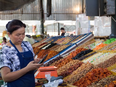 Markt in Kirgistan met kraam vol gedroogd fruit, noten en snoep, met verkoopster achter de toonbank.