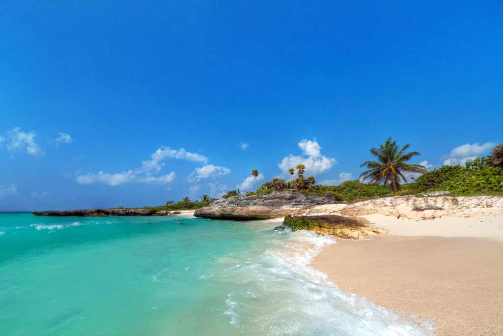 Tropisch strand in Mexico met turkoois water, palmbomen en rotsen tijdens groepsrondreis Mexico Chill & Adventure.