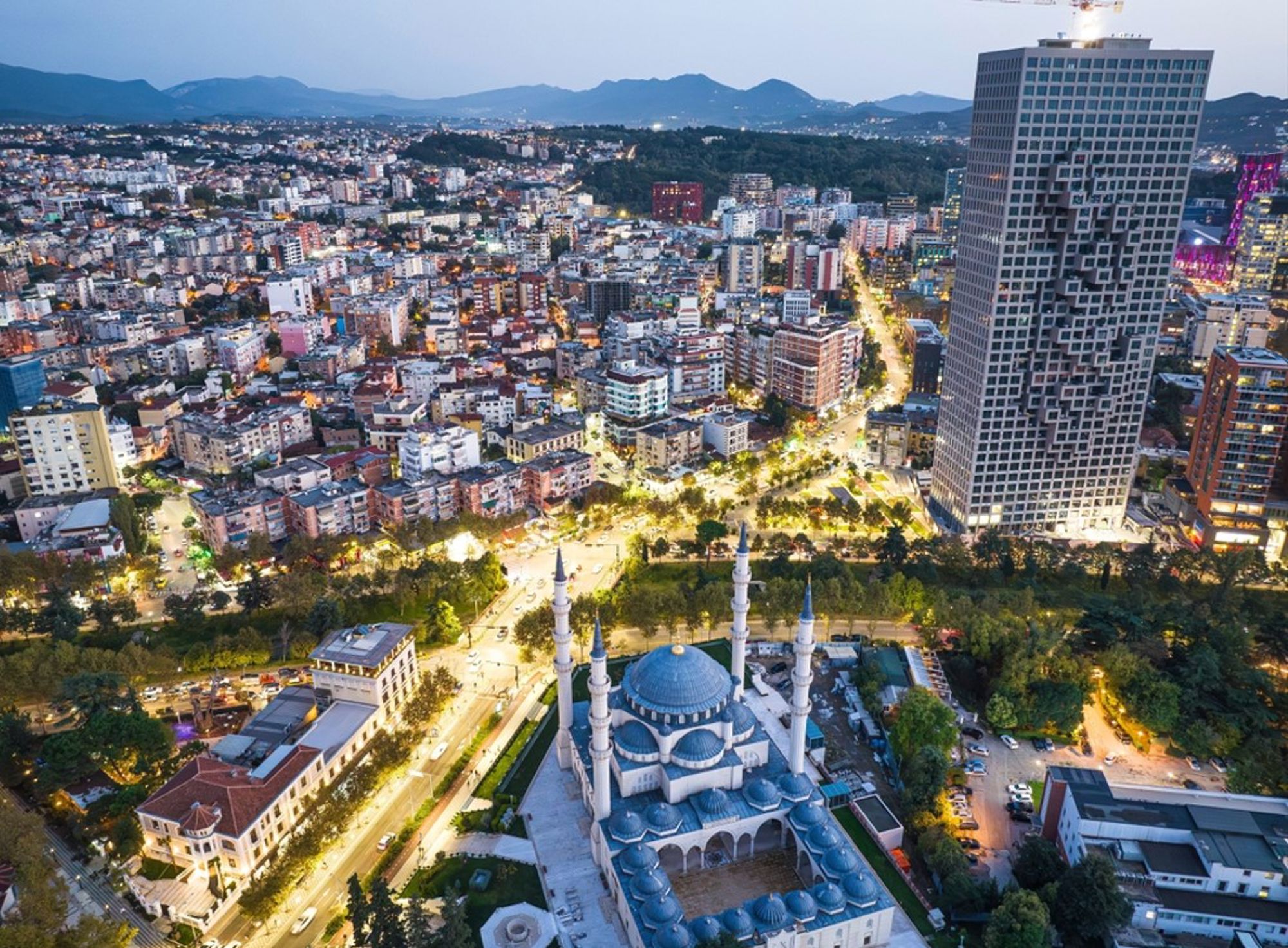 Avondzicht op Tirana met de Et'hem Bey-moskee en de moderne skyline op de achtergrond.