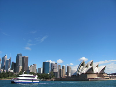 Sydney Opera House en skyline van Sydney aan de haven, met een boot op het water.