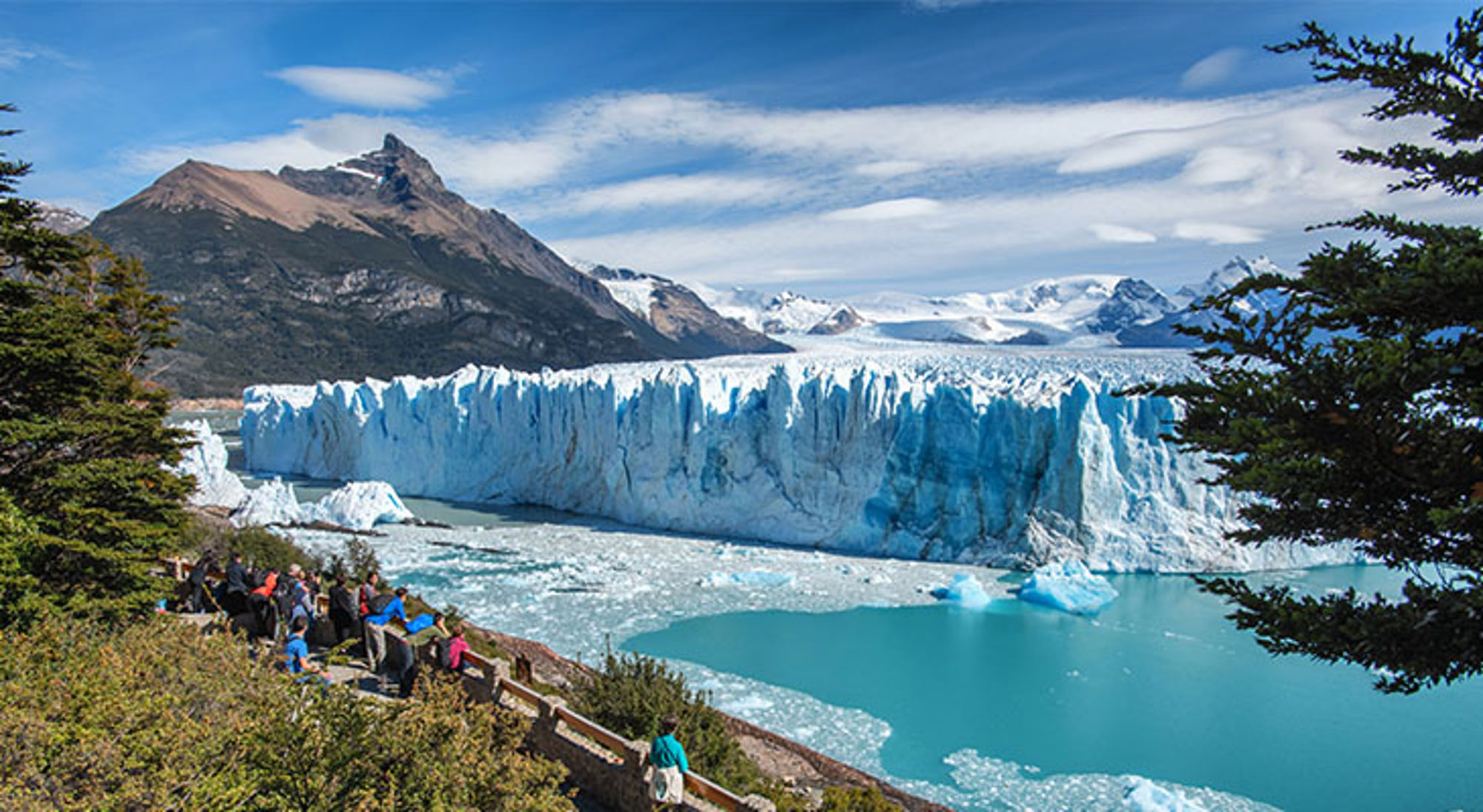 Mensen bewonderen het uitzicht op Perito Moreno Uitzicht op de Perito Moreno-gletsjer in Patagonië, met bezoekers op het uitkijkpunt en bergen op de achtergrond.