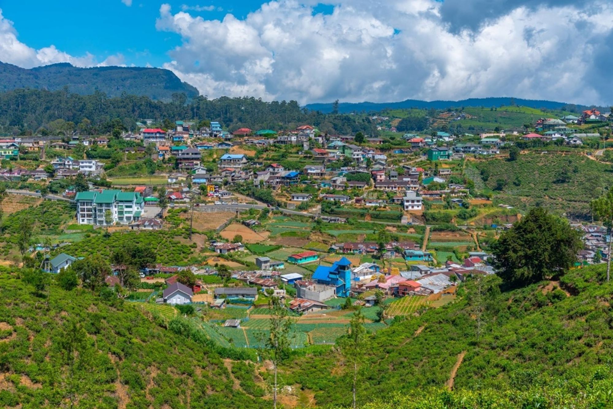 Panoramisch uitzicht op Nuwara Eliya in Sri Lanka, met kleurrijke huizen tussen groene heuvels en theeplantages.