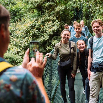 Gezin poseert op hangbrug in het regenwoud tijdens familiereis Costa Rica.