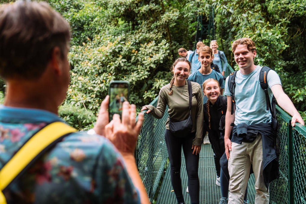 Gezin poseert op hangbrug in het regenwoud tijdens familiereis Costa Rica.