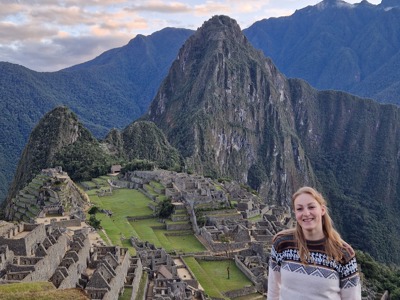 Uitzicht op Machu Picchu in Peru met reiziger op de voorgrond en de Andes op de achtergrond.