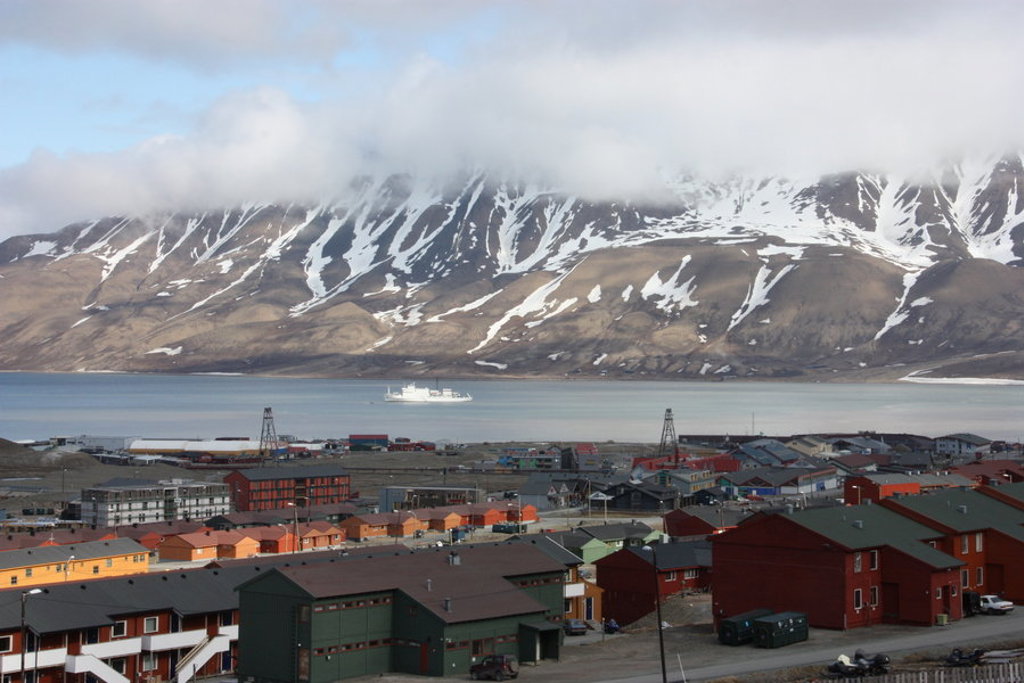 Longyearbyen op Spitsbergen met kleurrijke huizen aan de fjord en besneeuwde bergen op de achtergrond.