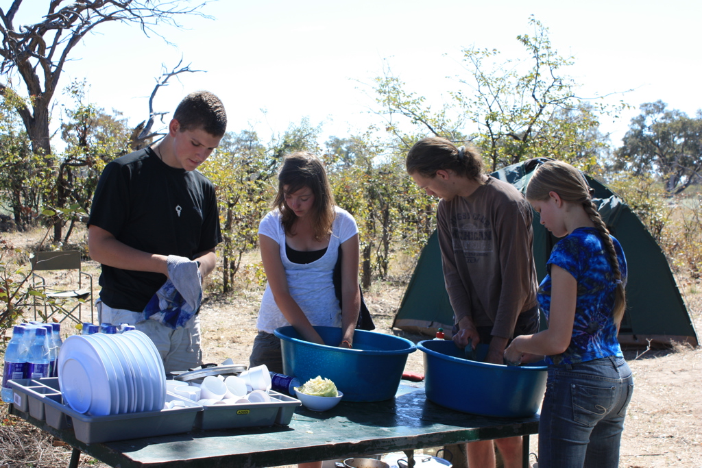 Gezin wast af bij een kampeerplaats tijdens familiereis Namibië, Botswana en Zimbabwe.