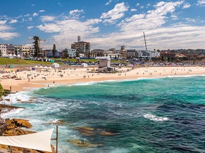 Bondi Beach in Sydney met strand, golven en skyline op de achtergrond.