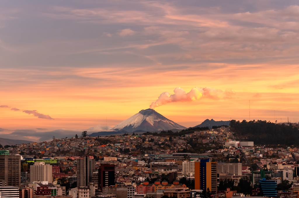 Zonsondergang boven Quito met de rokende Cotopaxi-vulkaan in Ecuador.