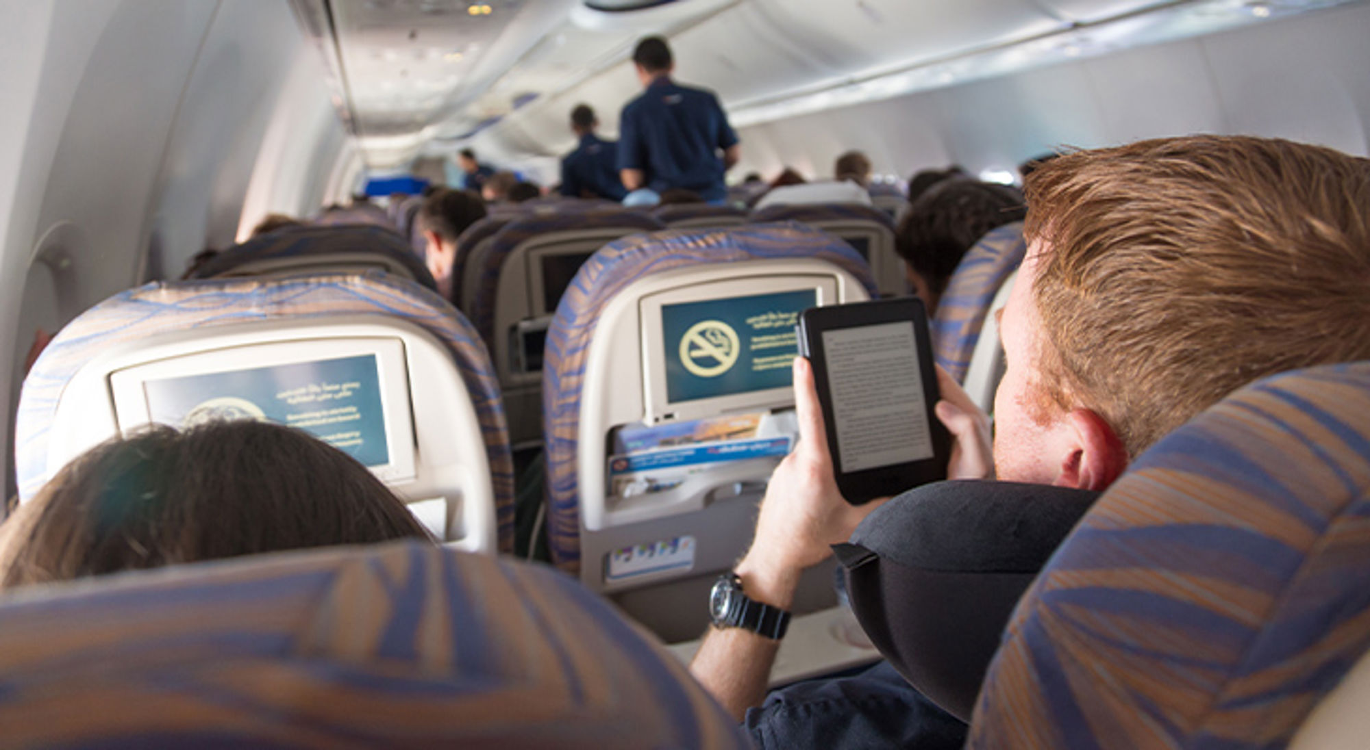 Cadeau voor reiziger e-reader Passagier leest op een e-reader in de cabine van een vliegtuig tijdens de vlucht.