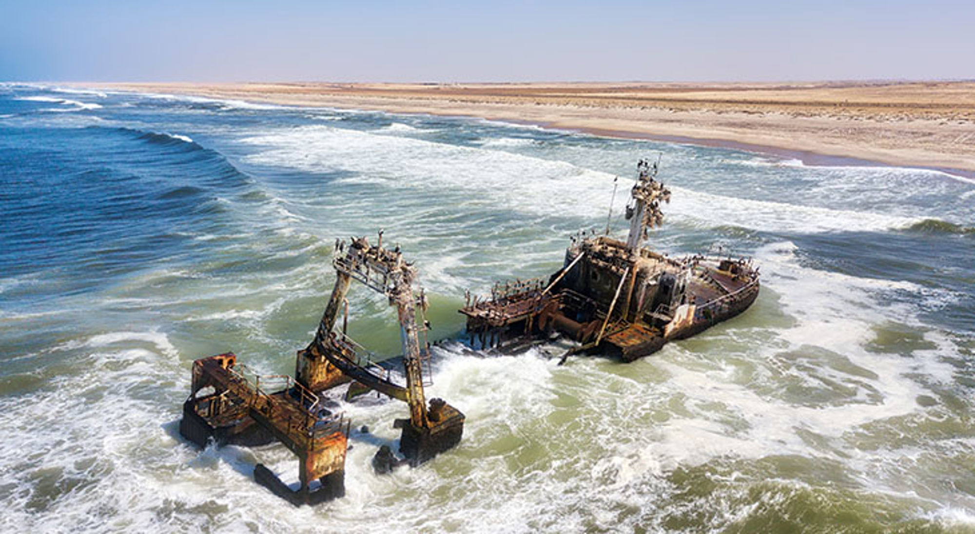 Scheepswrak langs de Skeleton Coast Scheepswrak aan de Skeleton Coast in Namibië, omringd door hoge golven en een uitgestrekte zandkust.