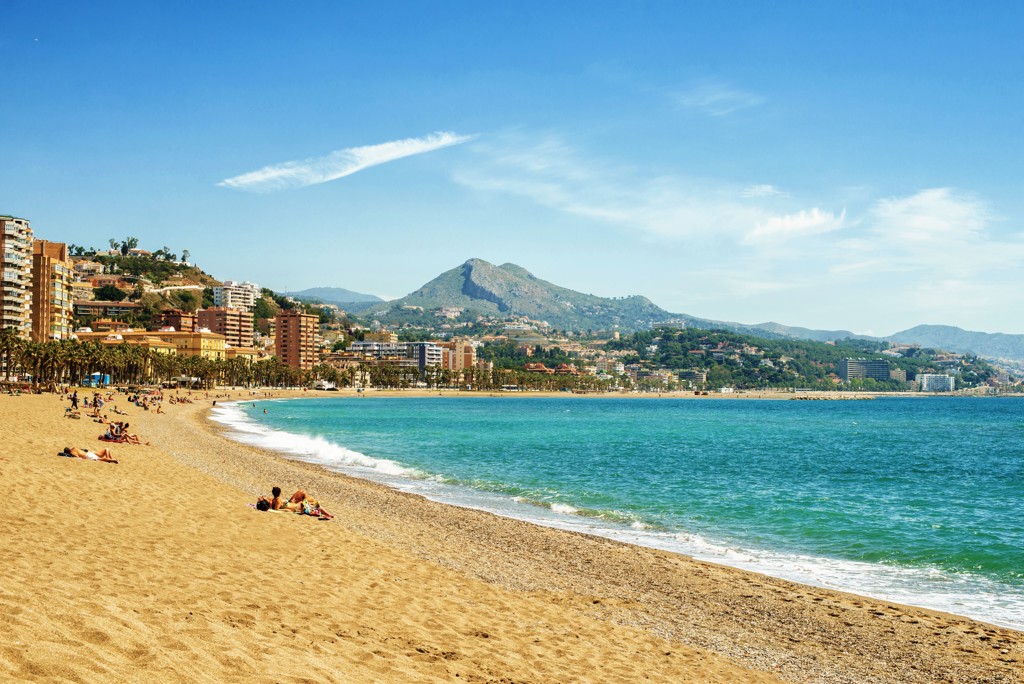 Zandstrand aan de Costa del Sol met boulevard, palmbomen en bergen op de achtergrond in Spanje.