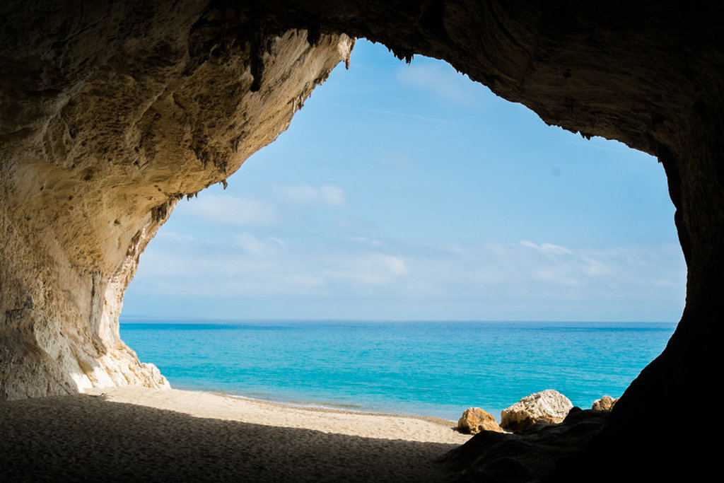 Uitzicht vanuit een grot op een zandstrand en turquoise zee op Sardinië, Italië.