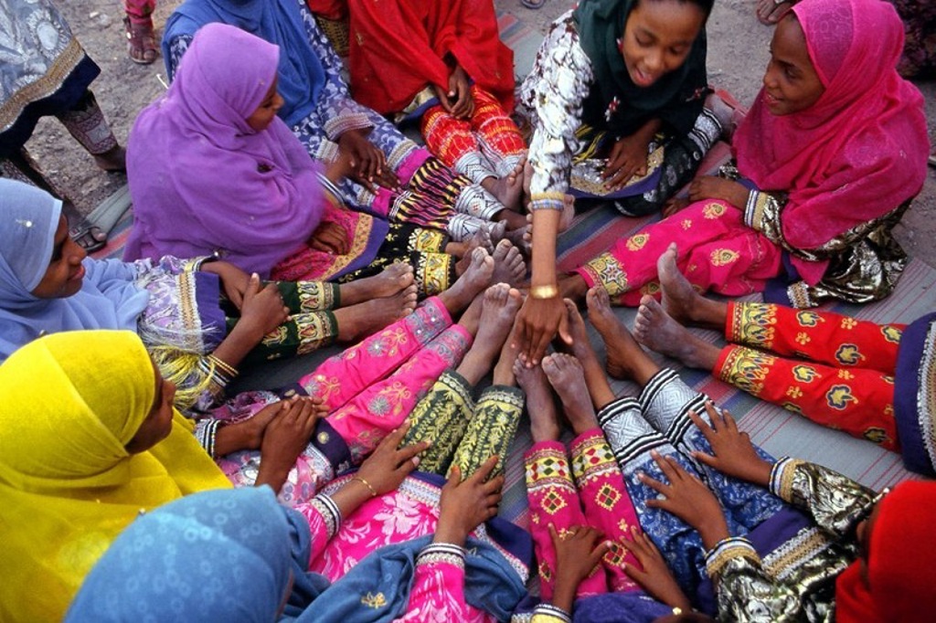 Vrouwen in kleurrijke kleding zitten in een kring op een mat tijdens een groepsrondreis in Oman.