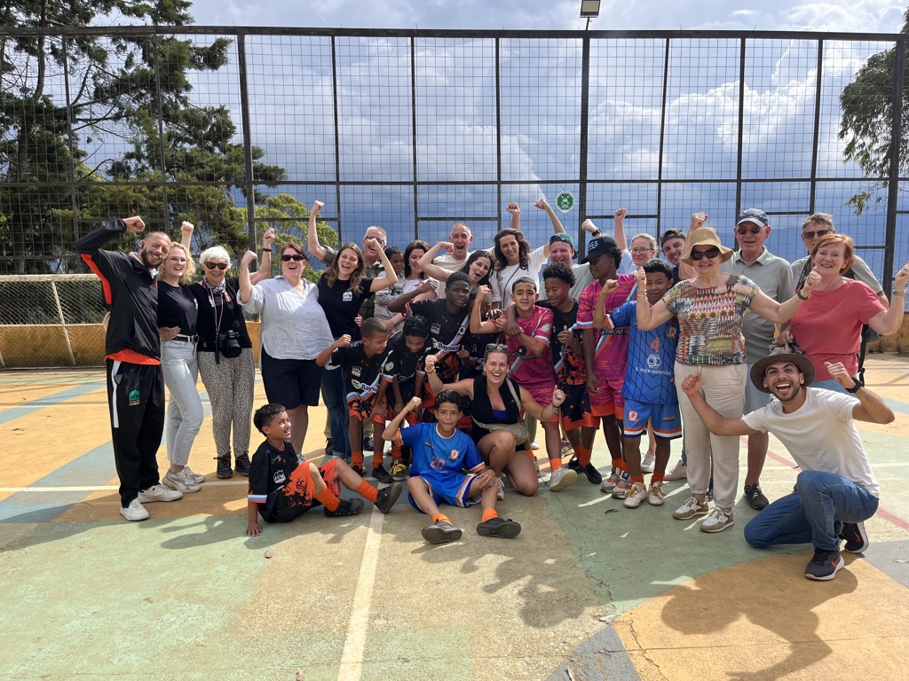 Groepsfoto tijdens familiereis Colombia met reizigers en lokale jeugd na een sportwedstrijd op een veld.