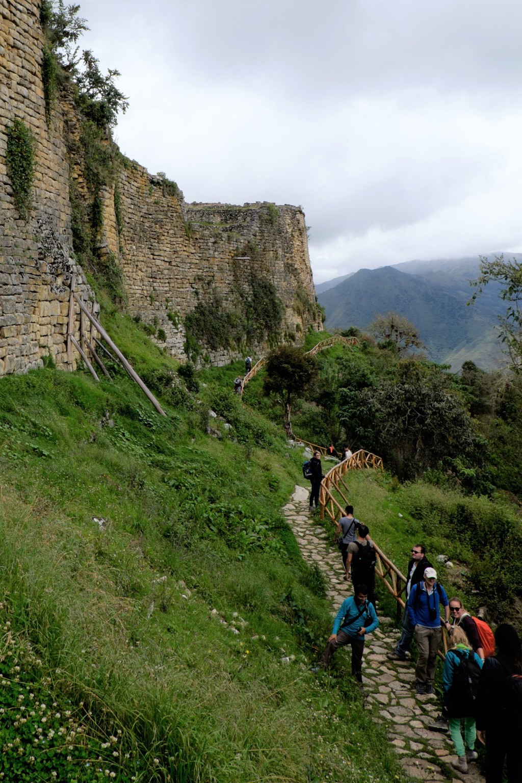 Wandelaars bij de ruïnes van Kuélap in Noord-Peru, met uitzicht op groene bergen.