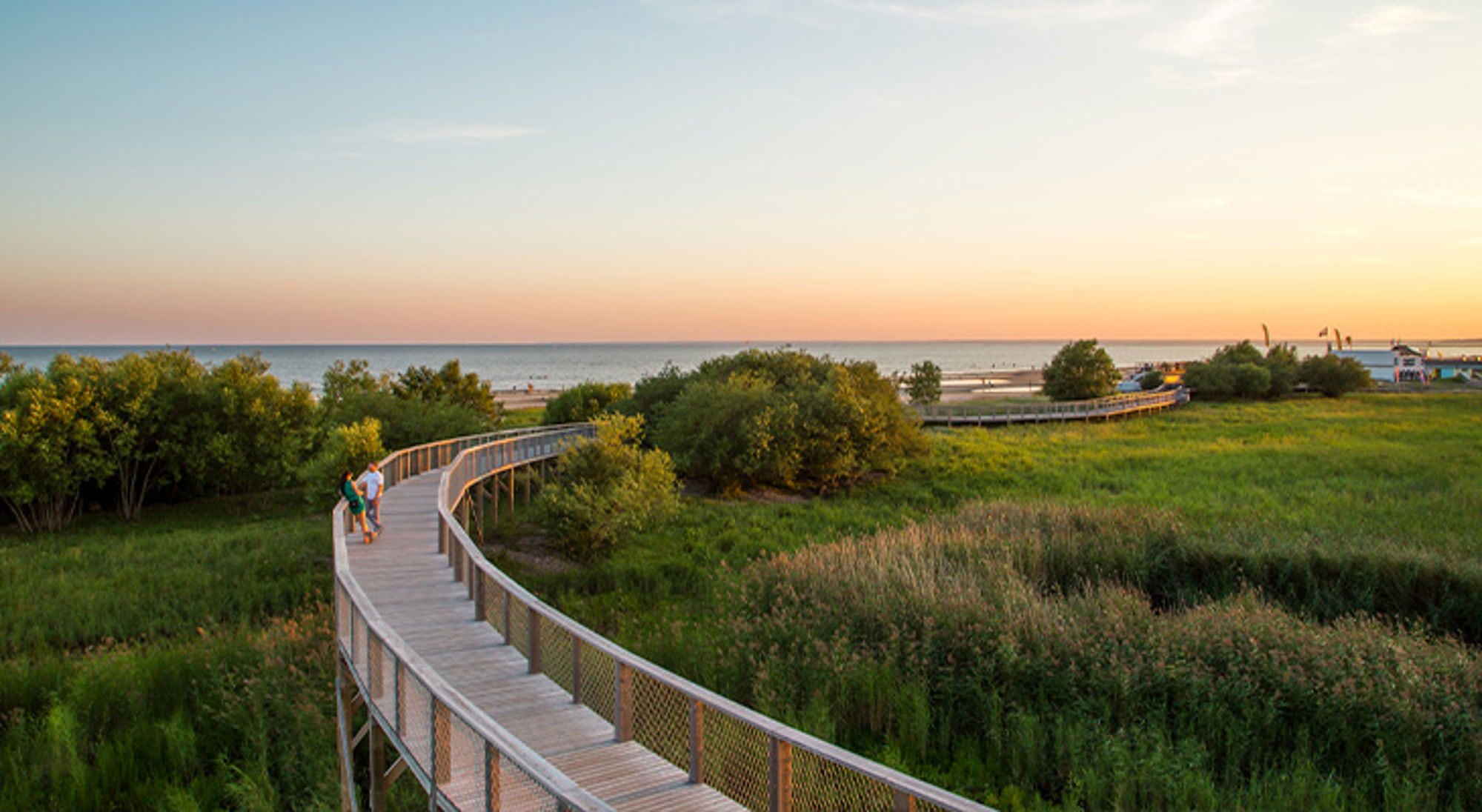 Pärnu Houten vlonderpad door duinen naar het strand bij zonsondergang.