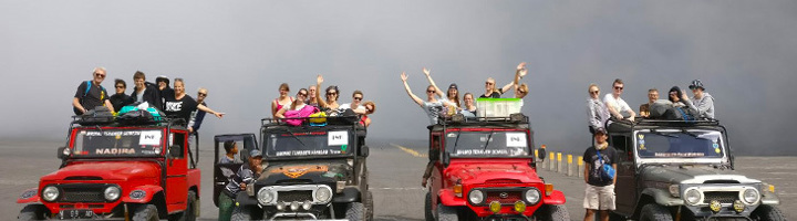 Gezinnen op jeepsafari tijdens een actieve familiereis, met kinderen en ouders op het dak van de terreinwagens.
