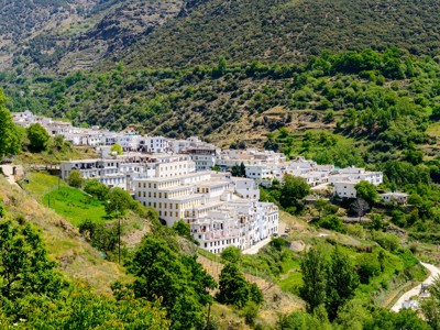 Wit bergdorp in de Alpujarras, Sierra Nevada, omringd door groene heuvels tijdens de wandelvakantie.