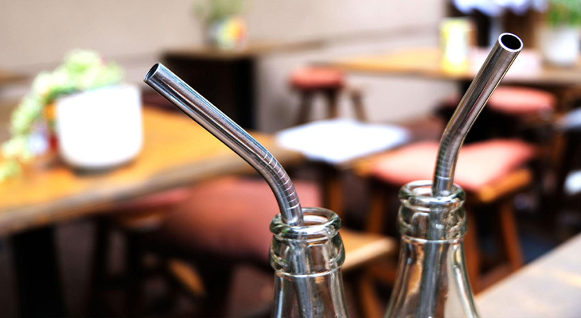 Metalen rietjes op reis Metalen rietjes in glazen flesjes op een cafétafel.