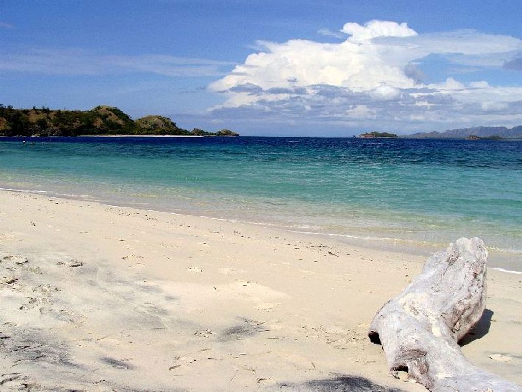 Wit zandstrand met turkooisblauw water en eilandjes op de achtergrond, Kleine Sunda eilanden Indonesië.