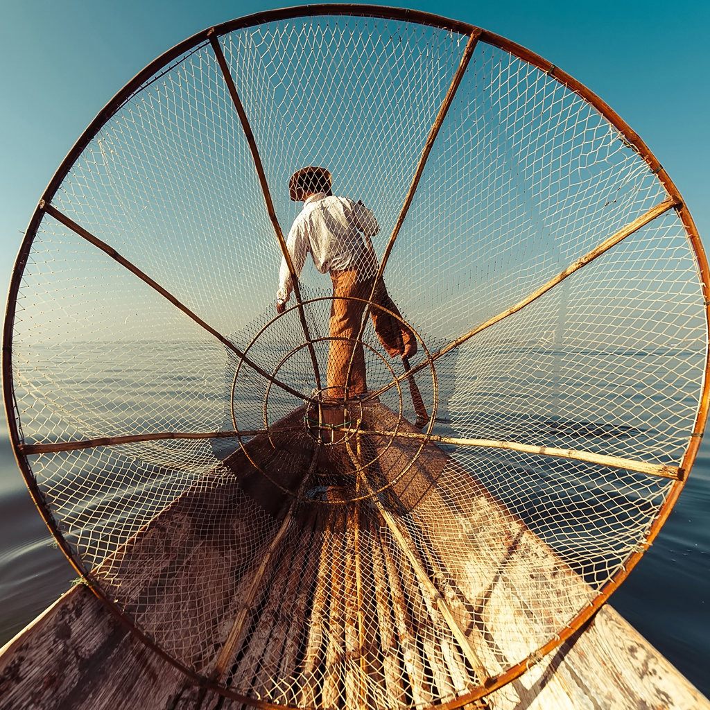Visser met groot net op een boot op het Inlemeer in Myanmar tijdens een groepsrondreis.
