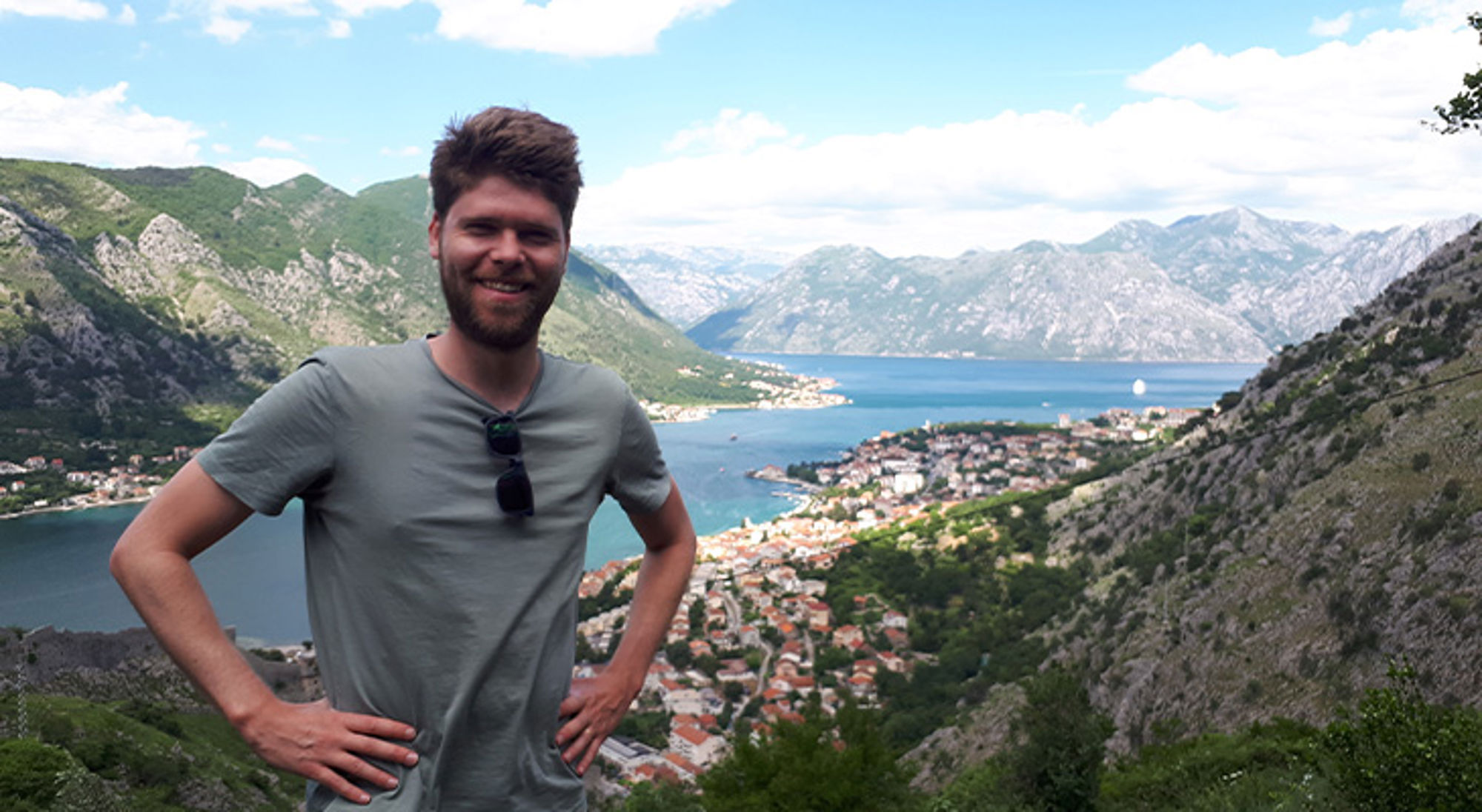 Joran in de Balkan Man poseert met uitzicht op de Baai van Kotor en de bergen in Montenegro.