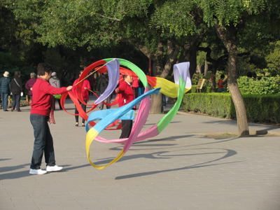 Mensen doen ochtendgymnastiek met kleurrijke linten in een park in China.