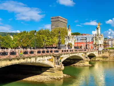 Puente del Arenal over de rivier Nervión in Bilbao, Spanje, met sierlijke beelden en blauwe lucht.